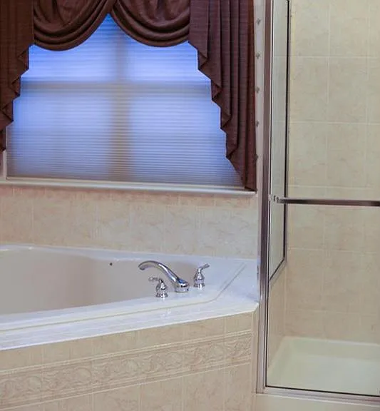 Master bathroom with a soaking bathtub and shower stall, part of the suite of master bedroom, with cathedral ceiling and double windows