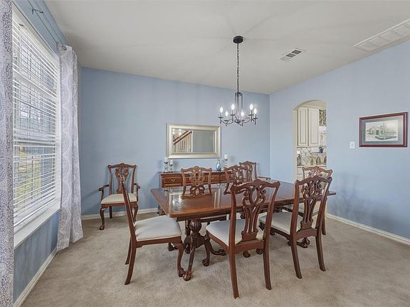 Dining space with arched walkways, light colored carpet, and hanging lights