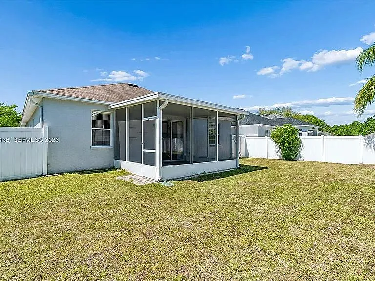 Spacious fenced backyard with a screened patio, offering room for outdoor seating, play, or weekend gatherings.