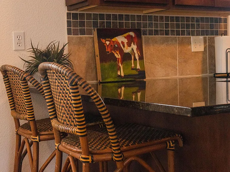 Large granite countertops with bar and bar chairs.