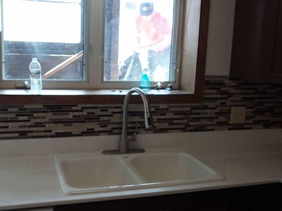 Kitchen sink with new faucet, garbage disposal and tile backsplash.