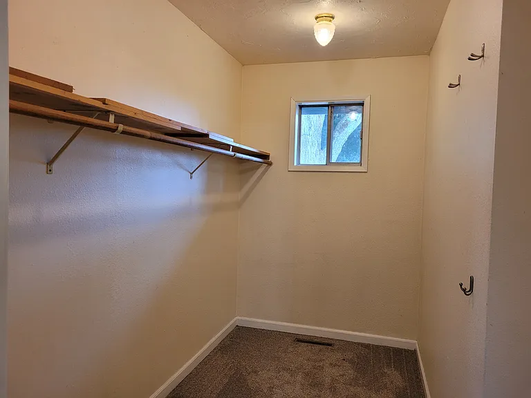 The master bedroom walk in closet has room for a dresser, new carpet and ample hanging and shelving space.