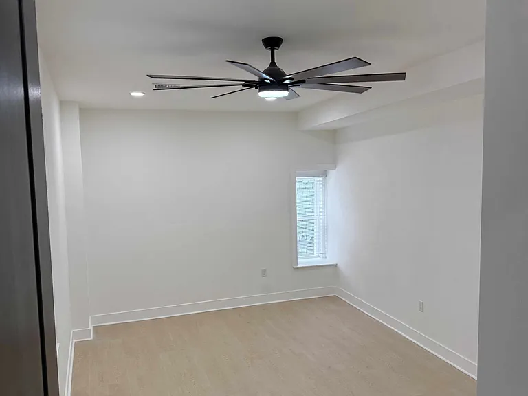 Large rear bedroom with large modern ceiling fan and large closet.