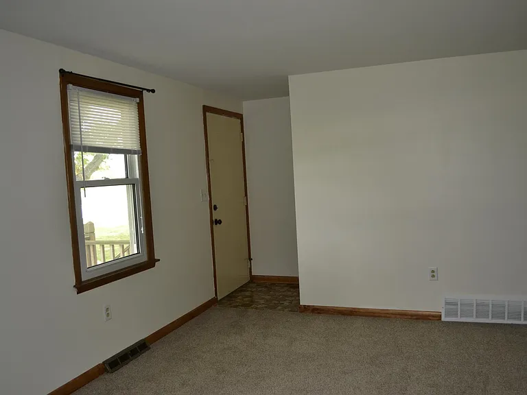 View of living room. It is carpeted, and has two windows.