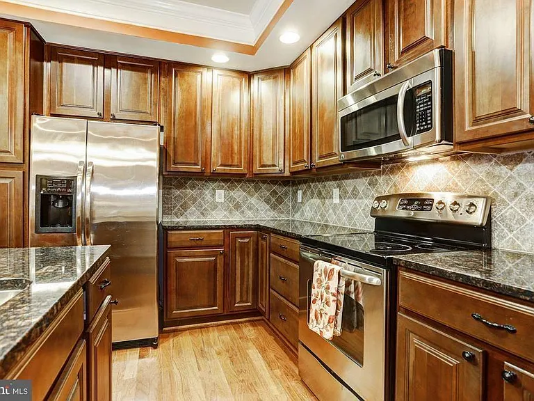 Kitchen with island, pantry, stainless steel appliances, granite countertops.