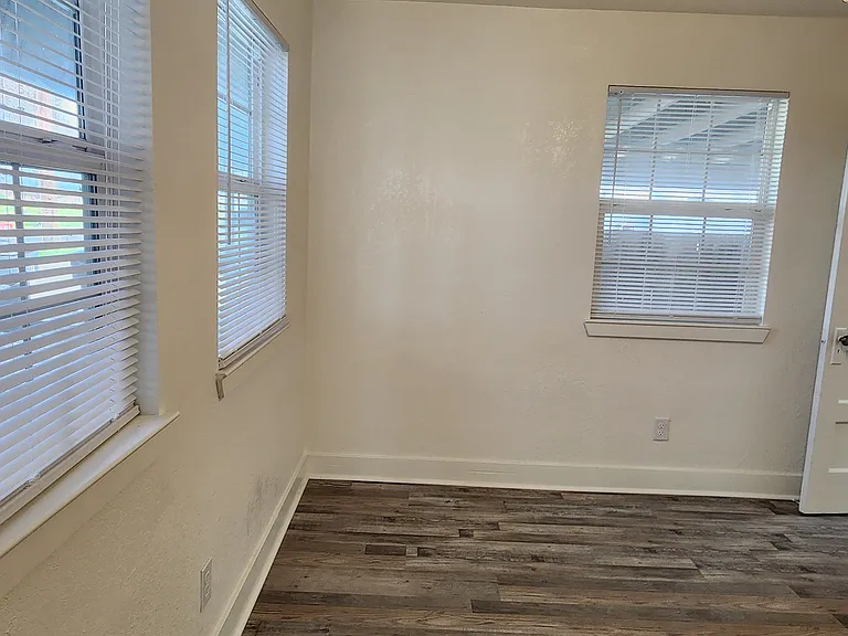 Front bedroom with ceiling fan and new flooring. Door to bathroom on right.