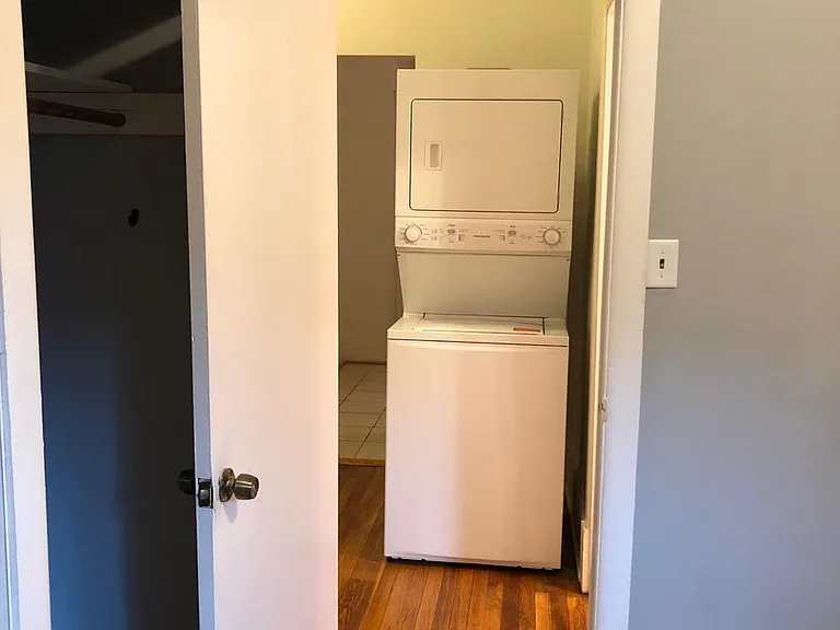 Stackable washer/dryer unit in hallway off of bedroom.