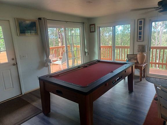 Common area with 65" tv on the wall, with 4 swivel chairs, and pool table, access to deck
