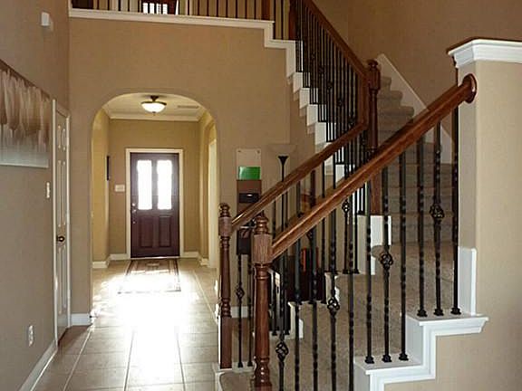 View to entry from den. Wrought iron banisters, 2 story ceilings, elegant lighting