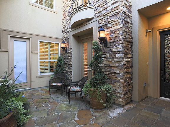 Inviting courtyard entry finished with slate and flagstone pathways, trickling wall fountain and beautiful iron front door