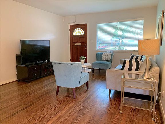 Living room with large picture window. 2-Inch Blinds on most of the windows. Beautifully refinished hardwood floors. Neutral paint colors throughout.