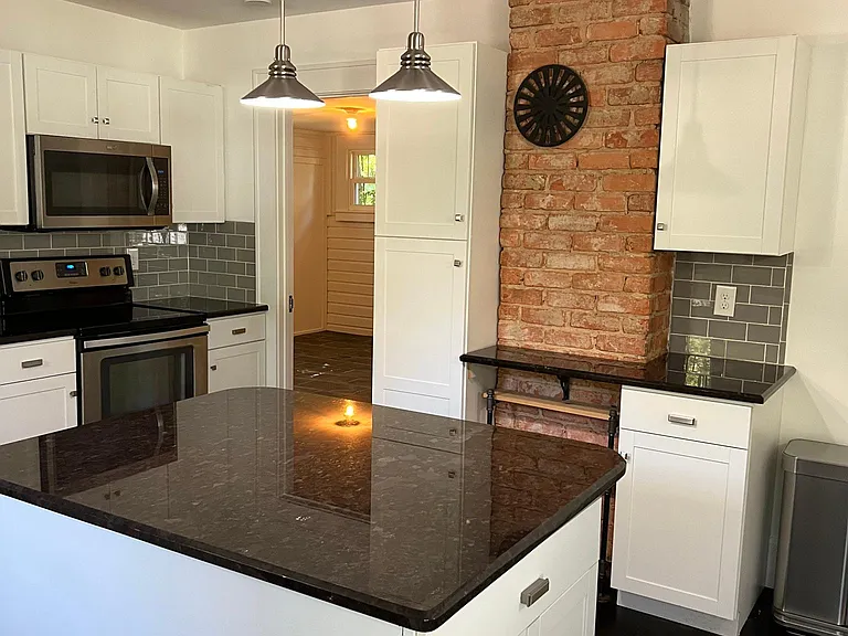 Exposed brick adds rustic and bohemian flare. Just off the kitchen through the doorway is the third bedroom.