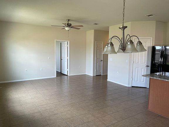 Living area has tile floors, ceiling fan, and is open to the kitchen/dining area for easy entertaining