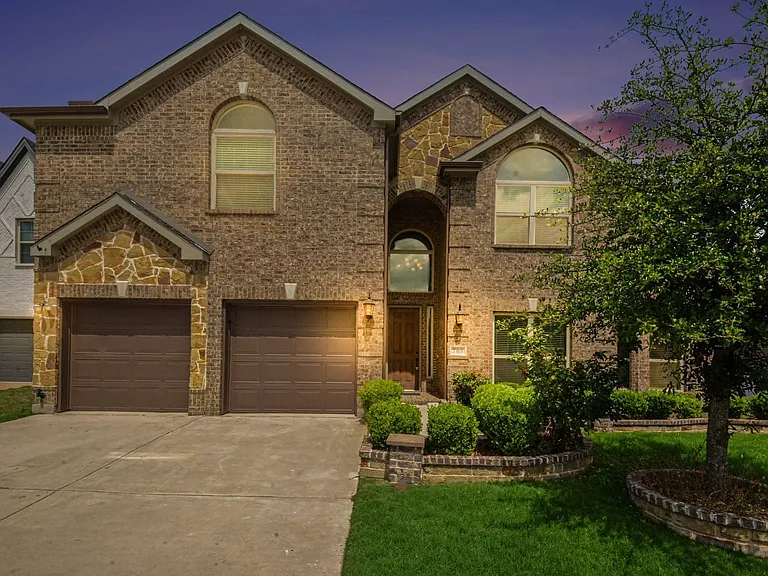 Brick and stone facade featuring a double garage and concrete driveway