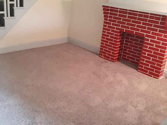 Newly carpeted living room with ceiling fan, fireplace, mantel and lovely 2-stage staircase.