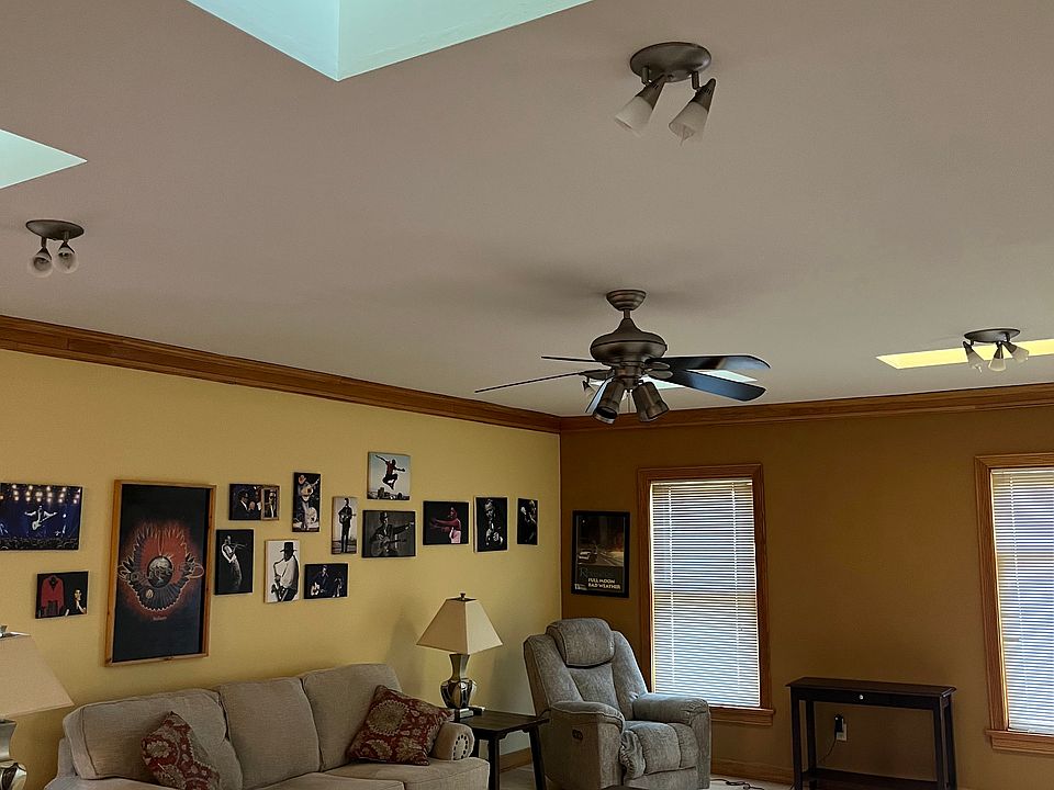 Living room features ceiling fan, skylights and overhead lighting.