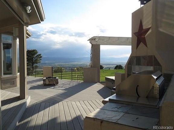 Built in grill area with fireplace and fridge on wrap around deck