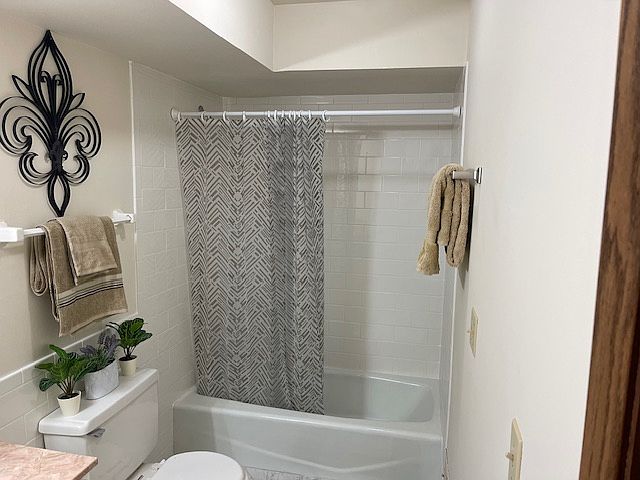Large bathroom includes tub and shower. White subway tile is easy to clean. Diamond shaped floor tile adds elegance