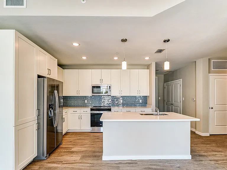Imperial Crossing Luxury Apartment Homes unit showing a modern kitchen with stainless steel appliances and white cabinets.
