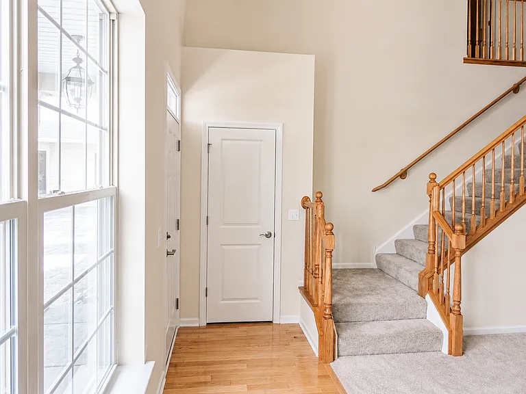 Front entry from Shermer Road, featuring a large window, coat closet, access to the living room, and stairs leading to the second floor.