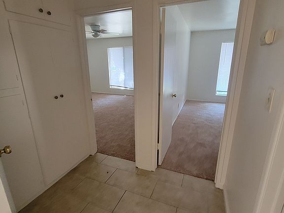 Tiled hall area with linen closet leads to a bedroom on right and one on left.