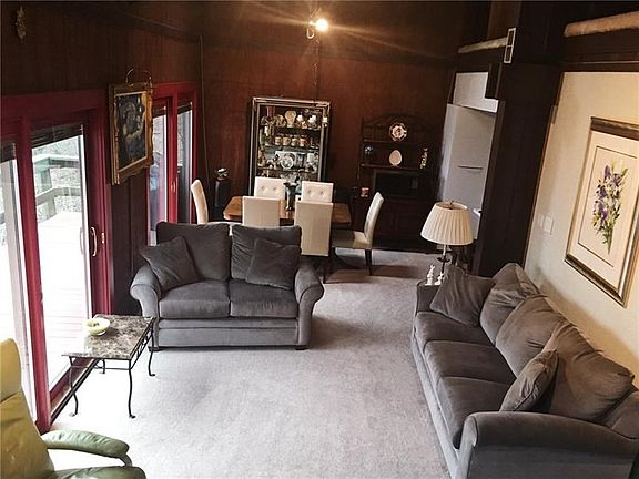 Open LIVING and DINING area.  New neutral tone carpet.  Cedar paneling.  Three newer extra large Pella sliders to access the dec