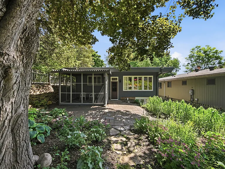 Private screened-in porch, outside patio, rock walls, and back yard (lower portion with many pollinator and flowering plants and large maple tree)
