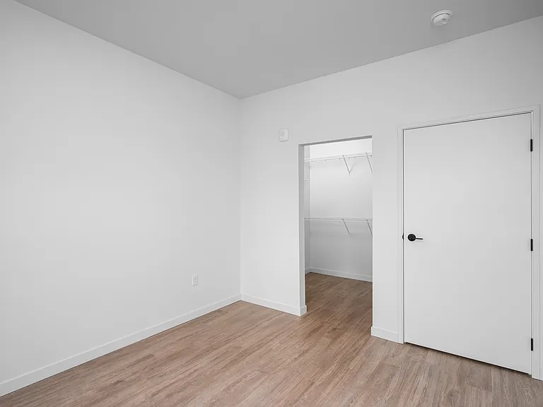 Bright, minimalistic bedroom with elegant wooden flooring and a spacious walk-in closet, perfect for stylish living. Bright, minimalistic bedroom with elegant wooden flooring and a spacious walk-in closet, perfect for stylish living.