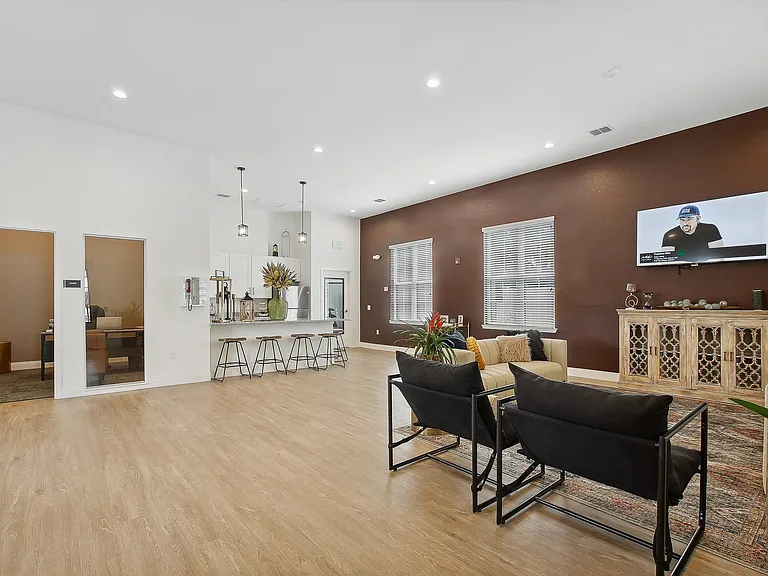 Bright and spacious living area with a modern open-concept design, featuring elegant hardwood floors and a stylish kitchen island with barstools.