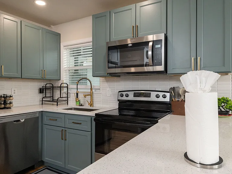 Bright, modern kitchen with stainless appliances, teal cabinets, and a spacious island_perfect for cooking, gathering, and enjoying a warm, stylish space.