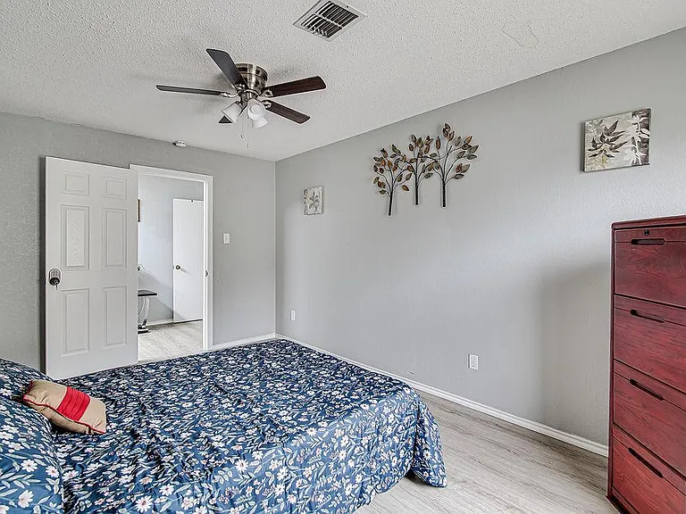 Spacious bedroom with ceiling fan, neutral walls, and room for a full bed plus dresser, with easy access to the hall.