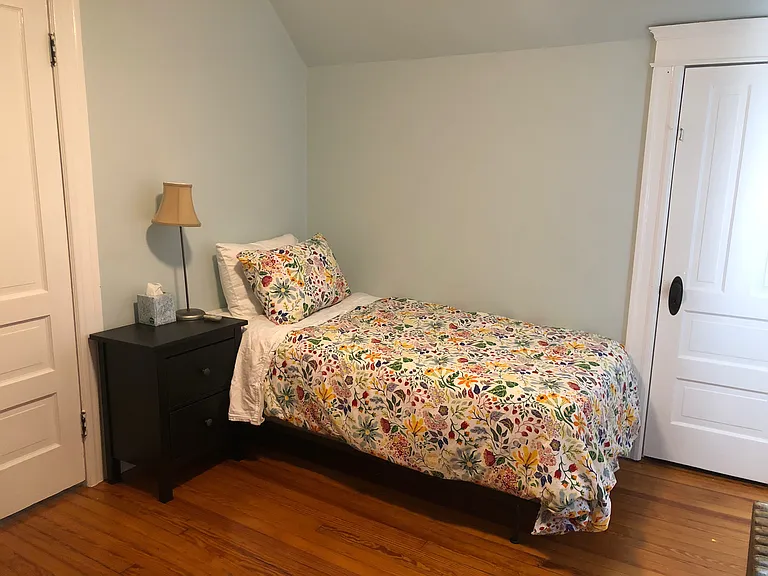 South-facing front bedroom has twin size bed, bedside table, small dresser, chair, ceiling fan & closet. This bedroom also has dedicated work space with desk and chair.