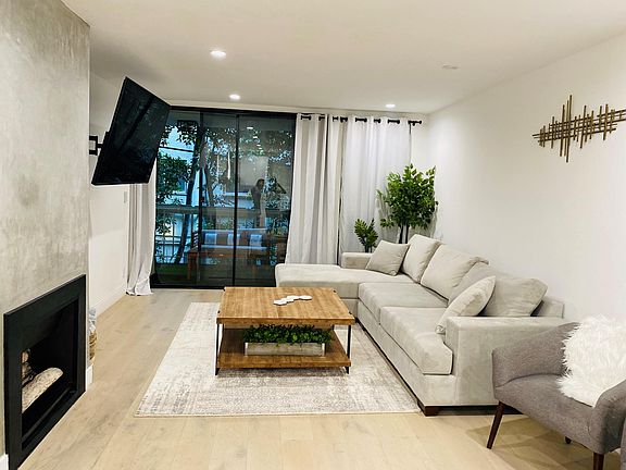 Upgraded furniture includes customized couch with light gray microfiber fabric, 65 inch TV, and West elm rug.