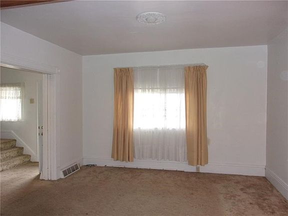 Spacious, bright living room with high ceilings and hardwood floors beneath carpet.