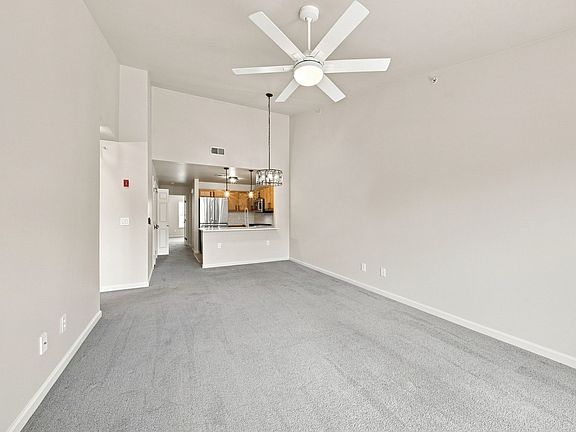Bright, open living and dining area with vaulted ceiling and sightlines into the kitchen.
