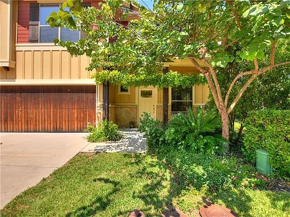 Front view of condo with 2 car garage and an amazing wisteria vine in front