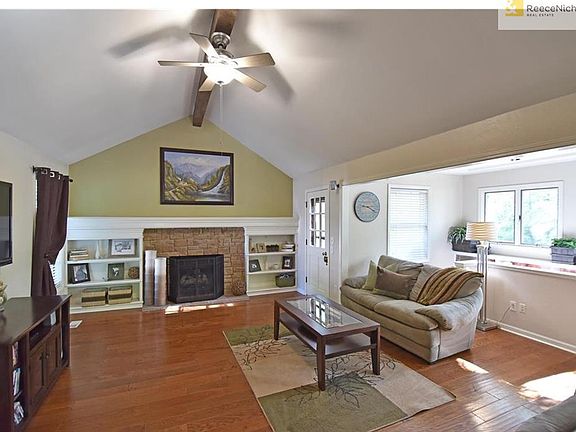 Spacious great room enhanced with gas-log fireplace, built-in and newer hardwood flooring