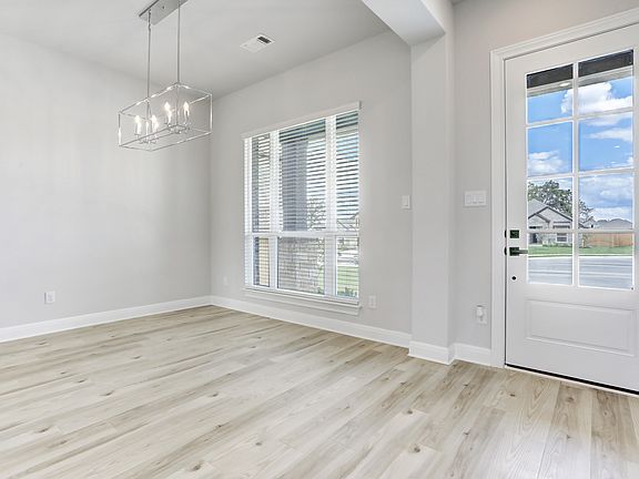 Formal dining room located off of the entry, with large windows and wood-style flooring.