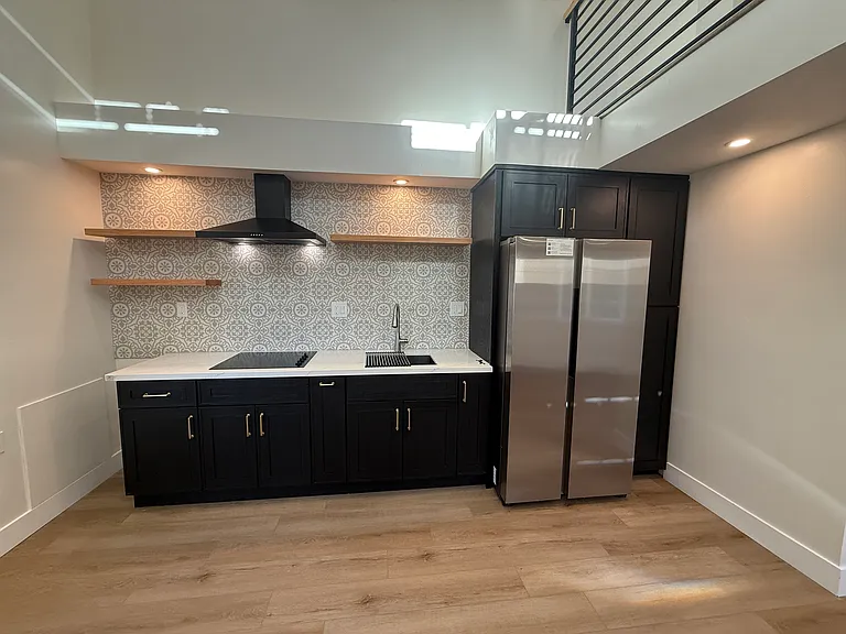 Stainless steel refrigerator, sink, and induction stove cooktop.