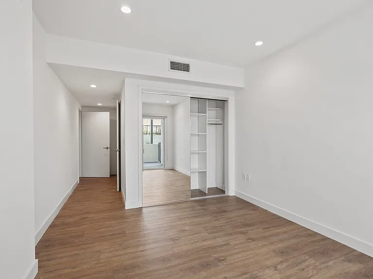 Bedroom with Mirrored Closet with Built-In Organizers, Vinyl Flooring, and Recessed Lighting