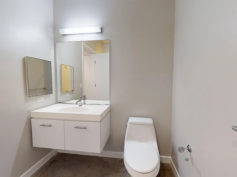 Apartment bathroom with polished-concrete flooring.