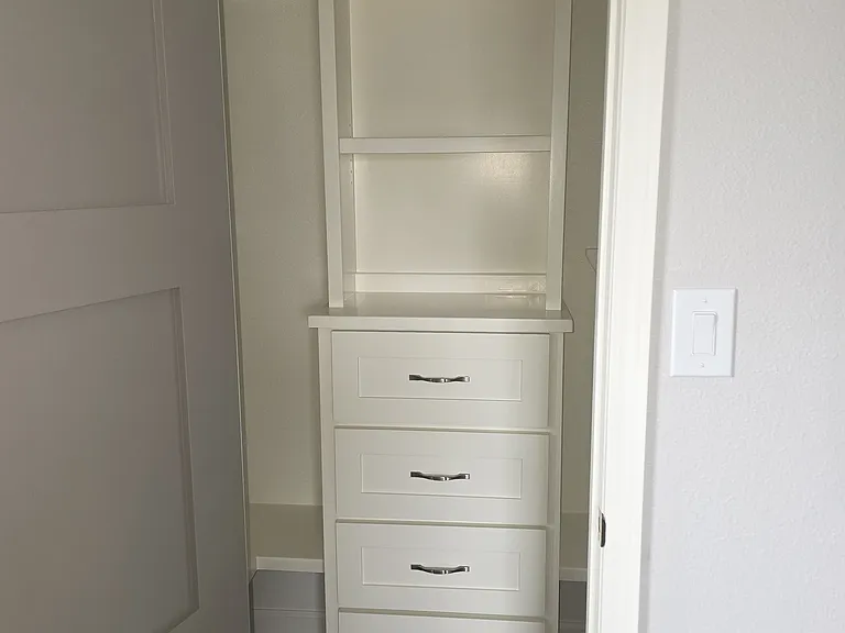 closet has a built-in dresser and shelves with metal rod holders.