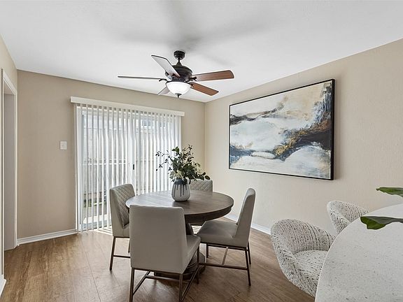 Dining area featuring wood-finish flooring, a ceiling fan with integrated lighting, and neutral wall tones.
