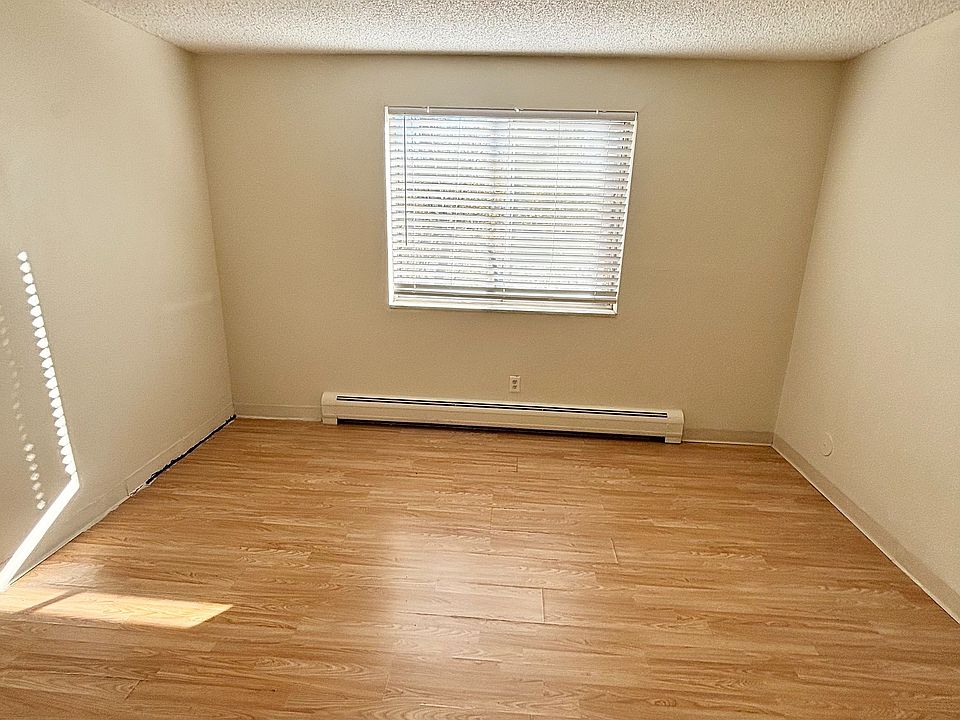 Bright and airy room featuring elegant wooden flooring, a ceiling fan, and a large window inviting natural light, perfect for a cozy living space.