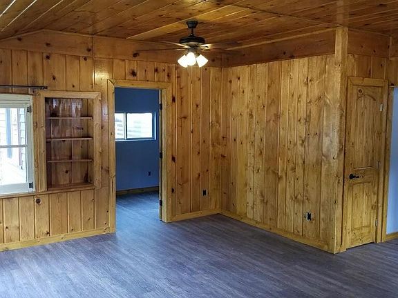 Gorgeous knotty pine living/dining room with two ceiling fans. Entry to bright and modern office.
