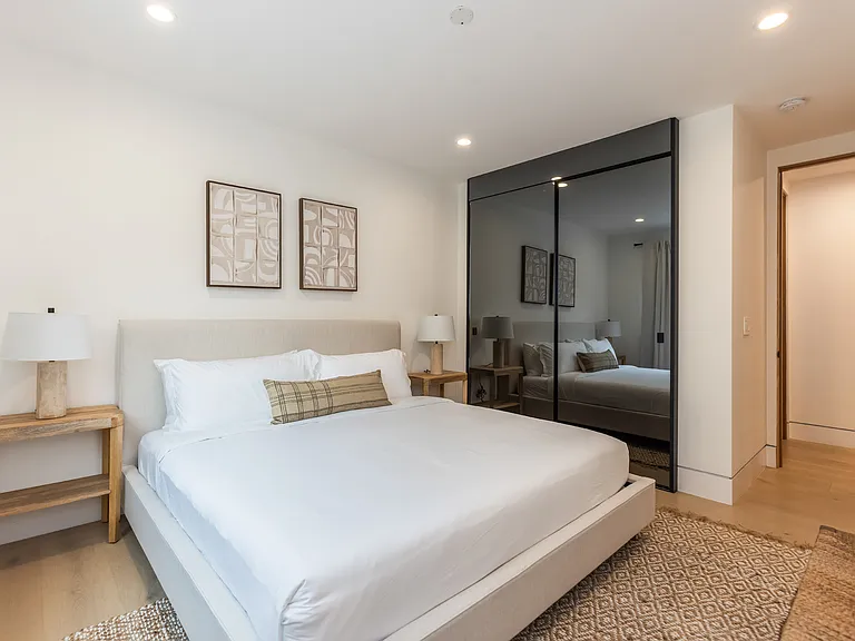Bedroom one, with black mirrored doors concealing the closet.