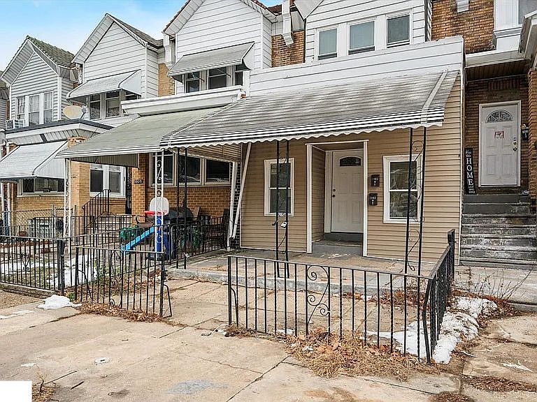 Brick-front duplex with a covered porch and gated front entry. Situated on a quiet residential block with street parking available. A small outdoor space at the front offers added convenience and versatility.