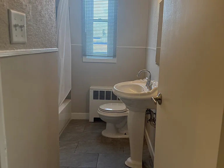 Bathroom with tile floor, and tub area, with pedestal sink.