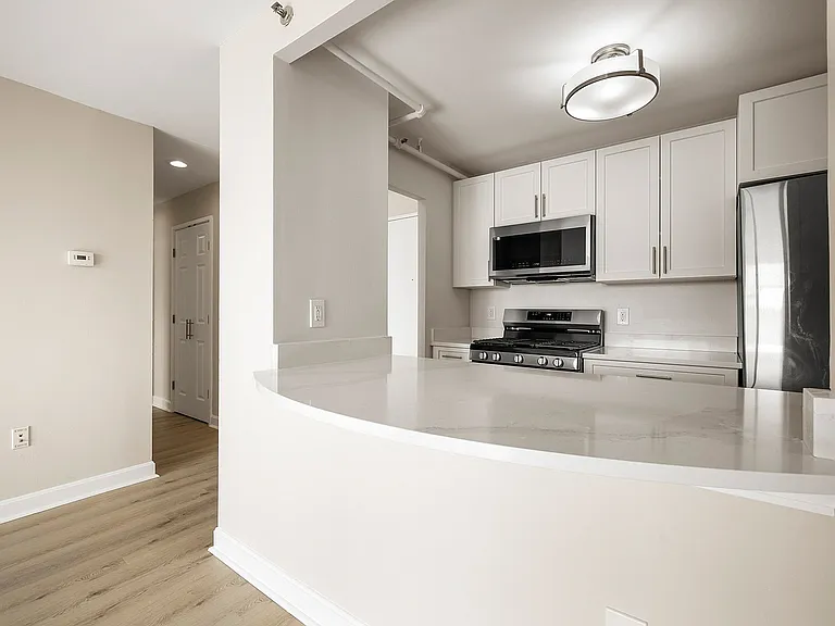 Modern kitchen with sleek statuario quartz countertops, white cabinets, stainless steel appliances, and gas stove for a sophisticated look at Parkside Place, apartments in Cambridge, MA