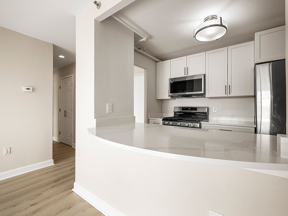Modern kitchen with sleek statuario quartz countertops, white cabinets, stainless steel appliances, and gas stove for a sophisticated look at Parkside Place, apartments in Cambridge, MA